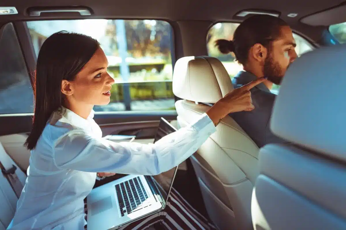 Professionnels échangeant sur la gestion d’une entreprise de transport Deux professionnels discutent avec un ordinateur portable à l'arrière d'un véhicule utilitaire